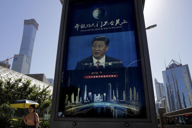 Mimoidoča v Pekingu na elektronskem zaslonu posluša govor predsednika Xi Jinpinga o nujnosti krepitve kitajske samozadostnosti na področju elektronike. FOTO: AP