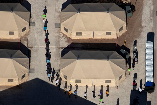 V objektu za pridržanje ob mehiški meji v teksaškem mestu Tornillo osebje vodi otroke priseljencev med šotori do prostora, v katerem strežejo hrano. FOTO: Mike Blake/Reuters
