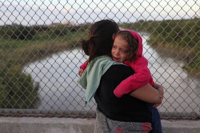 Begunka iz Hondurasa s triletno hčerjo v negotovosti čaka na mostu Brownsville &amp; Matamoros blizu Brownsvilla v Teksasu ob meji z Mehiko, potem ko so ji ameriške oblasti prepovedale vstop v ZDA. FOTO: Reuters