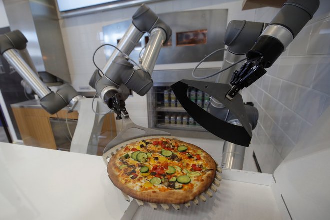 V francoskem mestu Montévrain blizu Pariza je na šovrumu francoske hrane zagonsko podjetje predstavilo robota pizzaiolo, ki popolnoma sam naredi pico pred očmi stranke. FOTO: Philippe Wojazer/Reuters
