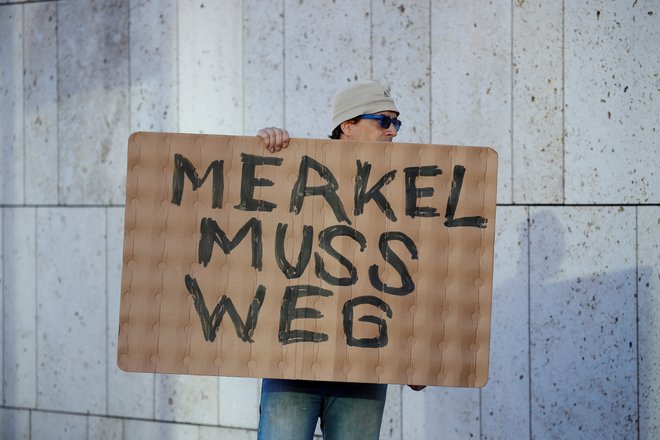 Protestnik pred sedežem Krščanskosocialne unije v Berlinu zahteva odhod Angele Merkel. FOTO: Axel Schmidt/Reuters