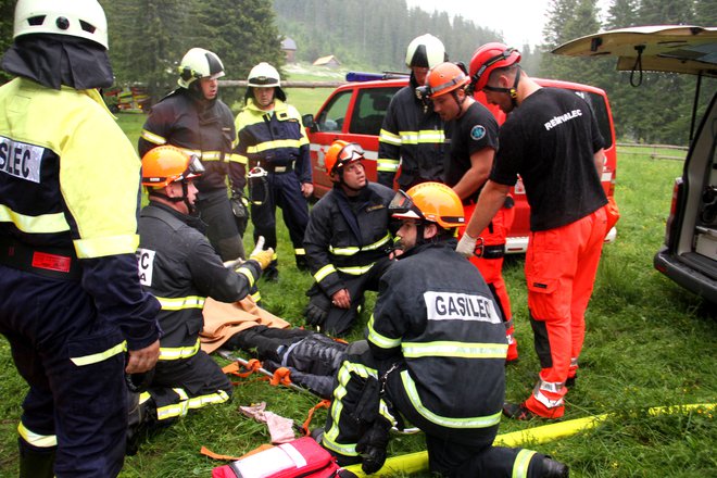 Gasilci in reševalci z roko v roki pomagajo poškodovanim. FOTO: Jože Miklavc