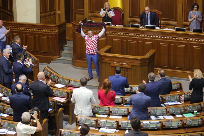 Na seji parlamenta v Kijevu je predsednik nogometne zveze Ukrajine in parlamentarec Andriy Pavelko nosil majico hrvaške nogometne reprezentance ter šal z napisom Hrvaška. Ukrajinska nogometna zveza je ponudila delovno mesto in finančno nadomestilo pred dnevi odpuščenemu pomočniku trenenerja hrvaške nogometne reprezentance Ognjenu Vukojeviću zaradi pro-ukrajinske politično motivirane izjave, ki je zaokrožila po spletu. Fifa ga je finančno kaznovala s 15.000 dolarji. Na instagramu je po zmagi nad Rusijo v videu skupaj s hrvaškim branilcem Domagojem Vido zavpil: &raquo;Slava Ukrajini!&laquo; Foto Oleksandr Kosmach Afp