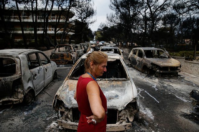 Lokalna prebivalka si v Mati ogleduje uničene avtomobile na eni izmed ulic. FOTO: Costas Baltas/Reuters