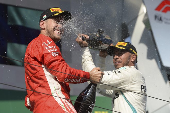 Lewis Hamilton (desno) je po včerajšnji zmagi na Hungaroringu takole s šampanjcem poškropil drugouvrščenega Sebastiana Vettla. FOTO: AP