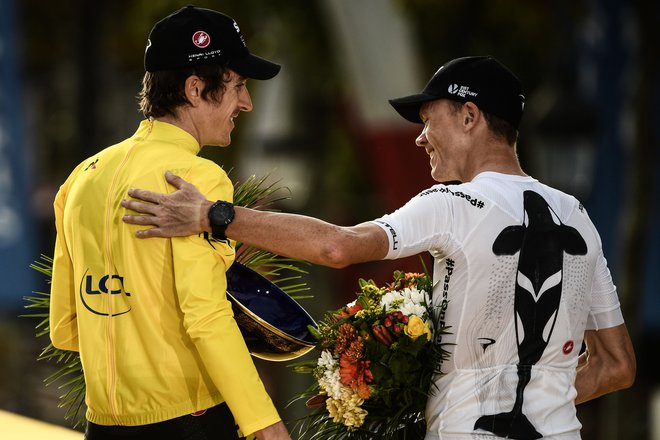 Tour de France 2018 winner Great Britain's Geraint Thomas (L), wearing the overall leader's yellow jersey, reacts with third-placed Great Britain's Christopher Froome (R) on the podium after the 21st and last stage of the 105th edition of the 