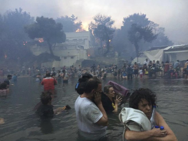 Ljudje so se pred ognjenimi zublji zatekli v morje. FOTO: Elia Kallia/AP