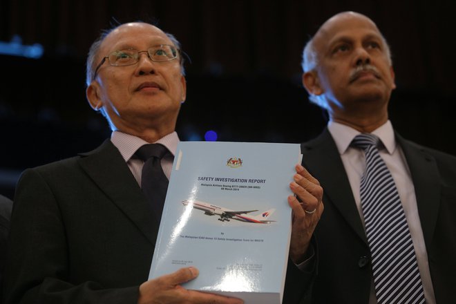 Glavni preiskovalec Kok Soo Chon (desno) v roki drži poročilo o izginulem malezijskem letalu MS370, ki obsega 495 strani. FOTO: Reuters