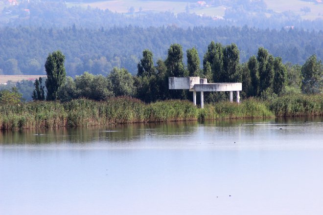 Jezero nad odlagališčem nenevarnih odpadkov in pregrado Cinkarne Celje v Bukovžlaku, desno vrh spomenika v Parku spomina Teharje. FOTO: Brane Piano