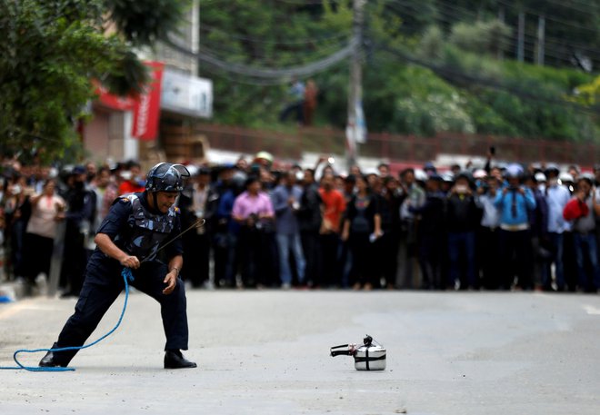 Nepalski policist po vsesplošnem preplahu v Lalipurju preverja pritisk v domnevni bombi. Pozneje se je pokazalo, da je bil lažni alarm. FOTO: Naveš Čitrakar/Reuters