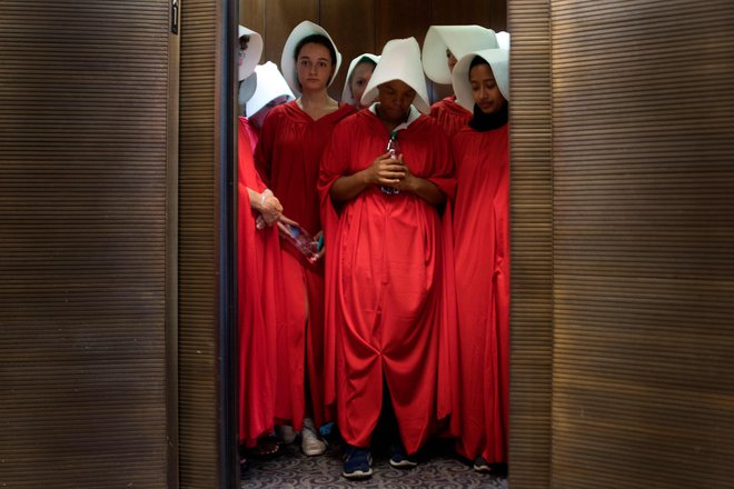 Ženske, oblečene v dekle iz serije Deklina zgodba (The Handmaid&#39;s Tale), stojijo v dvigalu senata, ko nominiranec vrhovnega sodišča Brett Kavanaugh začenja prvi dan zasliševanja pred ameriškim senatom v Capitol Hillu. Najnovejši kandidat Donalda Trumpa Brett
