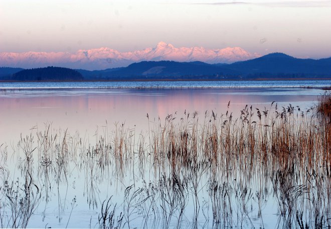 Takole je Cerkniško jezero videti pozimi, ko je napolnjeno z vodo. A tudi zdaj, ko vode skoraj ni, umirjena pokrajina v jesenskih odtenkih, zlasti gledano z višine, jemlje dih. Foto Mavric Pivk/Delo