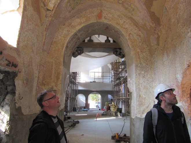 Župnik Tadej Linasi (levo) in višji konservator celjske enote ZVKDS Matija Plevnik si ogledujeta freske v zvonici. Zadaj je ladja cerkve z novim, večjim korom. FOTO: Špela Kuralt/Delo