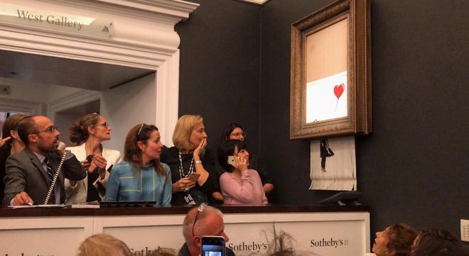 Trenutek po dražbi, na kateri je Banksyjevo Deklico z balonom doletel razrez. Fotografije Instagram