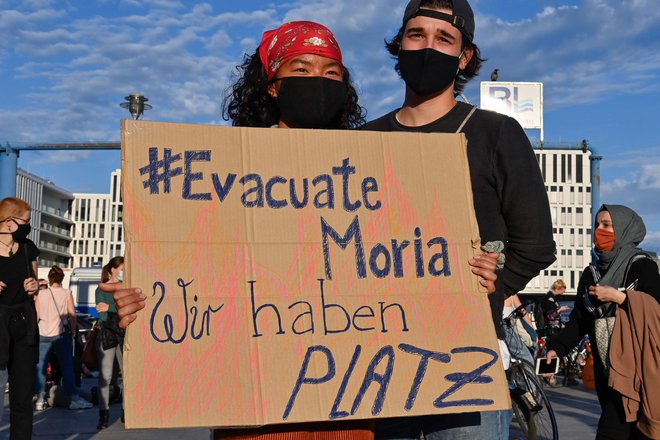 &raquo;Evakuirajte Morio. Pri nas je dovolj prostora!&laquo; piše na plakatu protestnikov v Berlinu, ki so se včeraj zavzeli za sprejem beguncev in migrantov z Lezbosa. FOTO: John Macdougall/AFP