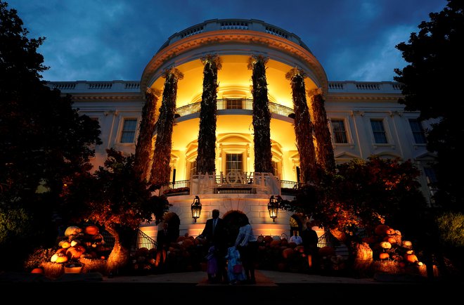 Bela hiša se je za praznik kopala v oranžni svetlobi, vojaški orkester pa je igral srhljive glasbene uspešnice. Foto Joshua Roberts/Reuters