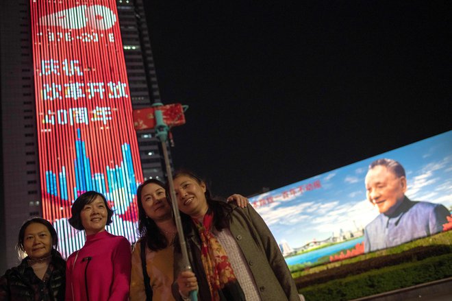 Ob obletnici začetka kitajskih reform in odpiranja proti svetu se ljudje fotografirajo pred panojem reformatorja Deng Xiaopinga. FOTO: AFP