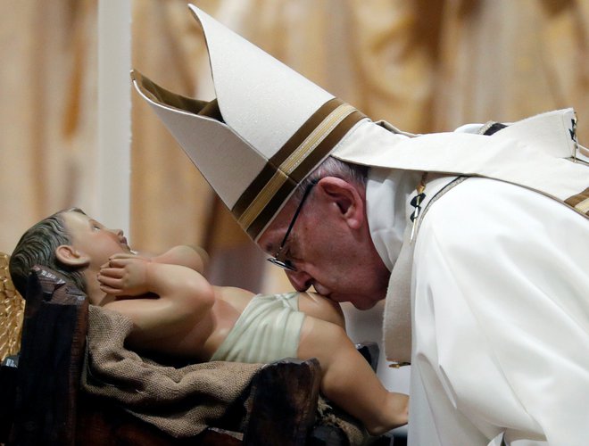 Papež Frančišek je med mašo na božični večer poljubljal kip Jezusa. FOTO: Max Rossi/Reuters