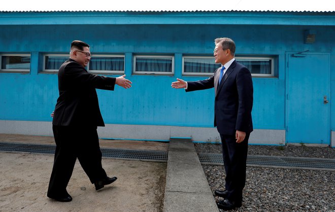 Zgodovinsko rokovanje severnokorejskega voditelja Kim Džong Una in južnokorejskega predsednika Mun Dže Ina znotraj demilitariziranega območja med obema Korejama. FOTO: Reuters