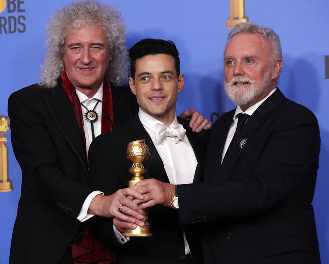 Rami Malek na nedeljski podelitvi zlatih globusov s članoma zasedbe Queen, kitaristom Brianom Mayem in bobnarjem Rogerjem Taylorjem. FOTO: Reuters