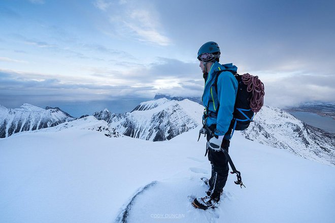 Hiker on winter summit of Hustind mountain peak, Flakstadøy, Lofoten Islands, Norway