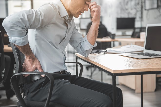 Neprekinjeno sedenje in napetost lahko privedeta do hudih bolečin, zaradi katerih je včasih potrebna dolgotrajna bolniška odsotnost. FOTO: Shutterstock