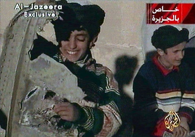 Deček na levi strani fotografije, ki v rokah drži razbitine ameriškega helikopterja, naj bi bil Hamza bin Laden. FOTO: Reuters