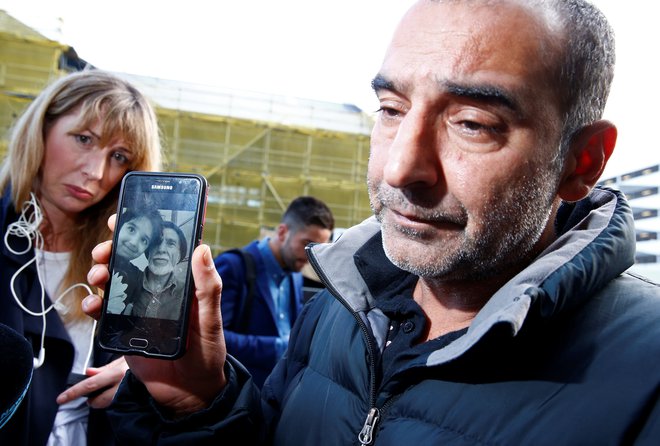 Omar Nabi (na fotografiji) novinarjem govori o svojem očetu (na sliki na telefonu) Daoudu, ki je bil prva identificirana žrtev napadov. FOTO: Edgar Su/Reuters
