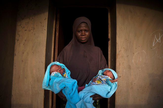 Muslimanka v rokah drži štiri dni stara identična dvojčka pred vhodom v svojo hišo v Igbo Ori. Foto Afolabi Sotunde Reuters