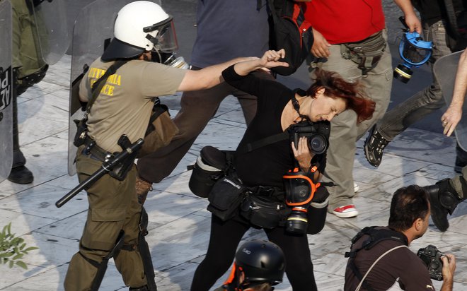 Grški policist je udaril fotoreporterkoTatianoBolari med demonstracijami v Atenah. Policisti so tisti dan napadli več novinarjev, ki so obravnavali proteste in ranili vsaj dva člana medijev.&nbsp;Foto Yannis Behrakis Reuters