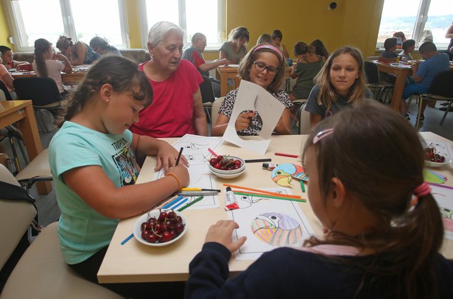 Stanovalci mariborskega doma Danice Vogrinec in otroci se skupaj igrajo miselne igre, rišejo, pojejo in si pripovedujejo zgodbe. Foto Tadej Regent