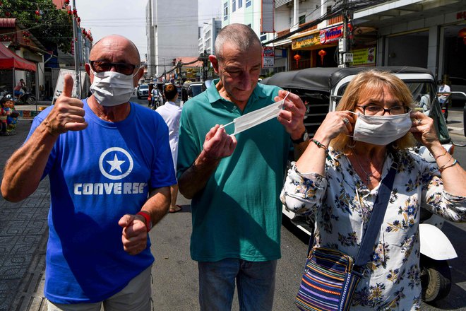 Strah pred novim virusom se širi po Aziji. Na fotografiji so turisti z zaščitnimi maskami v glavnem mestu Kambodže Phnom Penhu, kjer so ta teden uradno potrdili prvi primer okužbe. FOTO: AFP