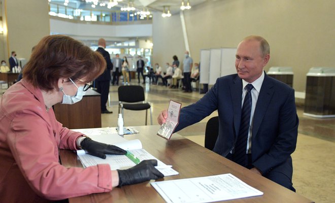 Vladimir Putin na volišču v Moskvi kaže svoj potni list. FOTO: Aleksej Družinin/AFP