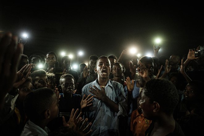 Letošnja zmagovalna fotografija <em>Jasen glas</em> prikazuje mladeniča iz Sudana, ki v Kartumu recitira protestno poezijo. Foto Jasujoši Čiba/AFP