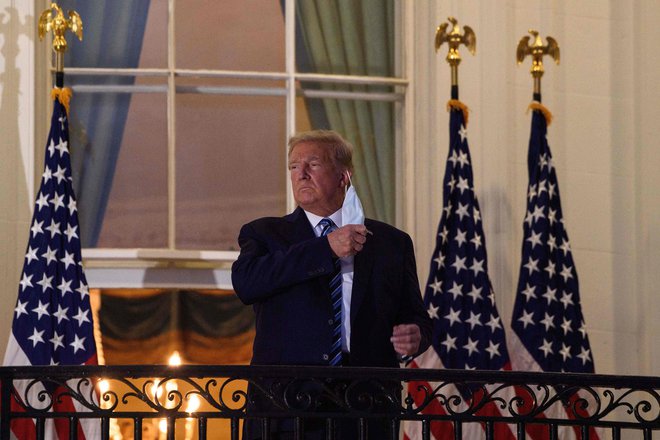 Predsednik Donald Trump je ob vrnitvi v Belo hišo snel zaščitno masko in covid-19 spet primerjal z gripo. Foto Nicholas Kamm/AFP