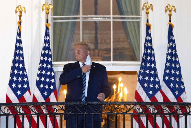 Ameriški predsednik Donald Trump si je po prihodu iz bolnišnice pred Belo hišo demonstrativno odstranil zaščitno masko. FOTO: Win McNamee/AFP