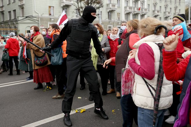 Beloruske upokojenke se na protestnem shodu v Minsku, na katerem zahtevajo odstop avtoritarnega voditelja in nove poštene volitve, soočajo z uslužbencem organov pregona. Beloruska policija je včeraj zagrozila, da bo proti protestnikom izstrelila prave naboje. Protesti trajajo že od sporne zmage Lukašenka na volitvah 9. avgusta. FOTO: Stringer/AFP