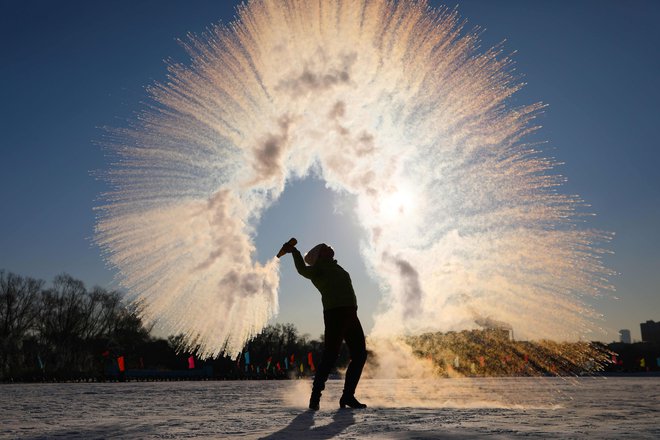 Na severovzhodu kitajske province Liaoning je ženska vrgla v zrak vročo vodo, ki se zaradi izredno nizkih temperatur takoj kondenzira v ledene kristale. FOTO: Stringer/Afp