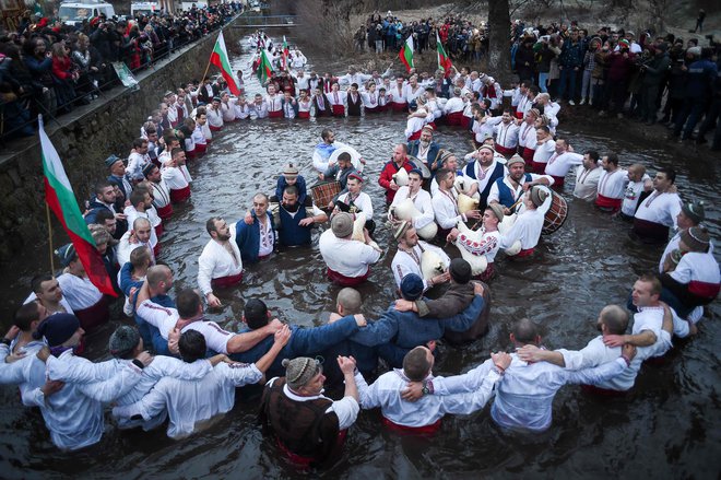 Bolgarski moški izvajajo tradicionalni ples horo v ledenih zimskih vodah reke Tundža v mestu Kalofer med praznovanjem pravoslavnega božiča, kljub omejitvam zaradi pandemije. Pravoslavni duhovnik vrže križ v reko, tisti, ki ga bo ujel prvi, naj bi ostal zdrav skozi vse leto, pa tudi vsi, ki plešejo v ledenih vodah. FOTO: Nikolay Doychinov/Afp