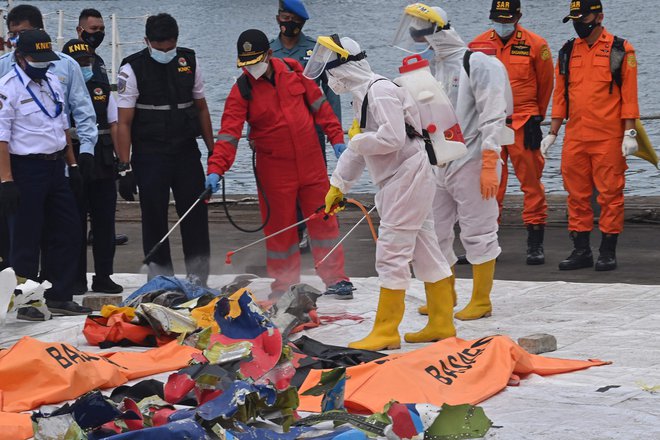 Pripadniki indonezijskega Rdečega križa ob predmetih, ki so bili na letalu družbe&nbsp;Sriwijaya Air. FOTO:&nbsp;Adek Berry/AFP