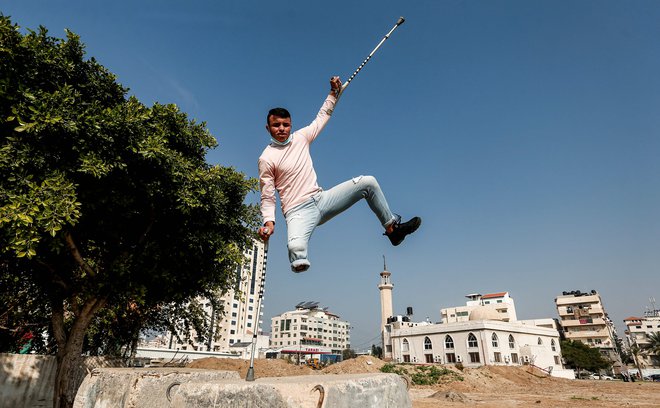 Palestinskemu najstniku je izstrelek odnesel nogo, a se priljubljeni dejavnosti ni odpovedal. FOTO: Mahmud Hams/AFP