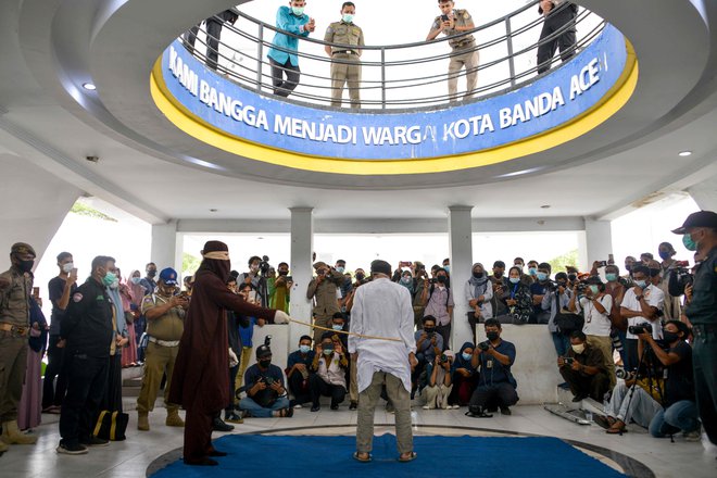 V Banda Acehu je član šeriatske policije s palico iz ratana javno prebičal človeka, ki so ga obtožili homoseksualnega seksa. Aceh je edina regija v Indoneziji, največji muslimanski državi, ki vsiljuje šeriatski islamski zakon. FOTO: Chaideer Mahyuddin/Afp
