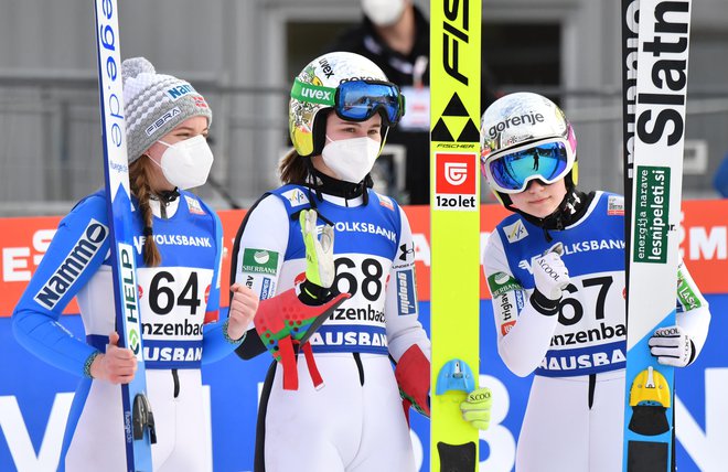 Nika Križnar (na sredini) in Ema Klinec (desno) sta Sloveniji priskakali zgodovinsko prvo dvojno zmago v svetovnem pokalu. Skakalkama iz SSK Žiri je družbo na odru za najboljše delala Norvežanka Eirin Maria Kvandal (levo). FOTO: Barbara Gindl/AFP