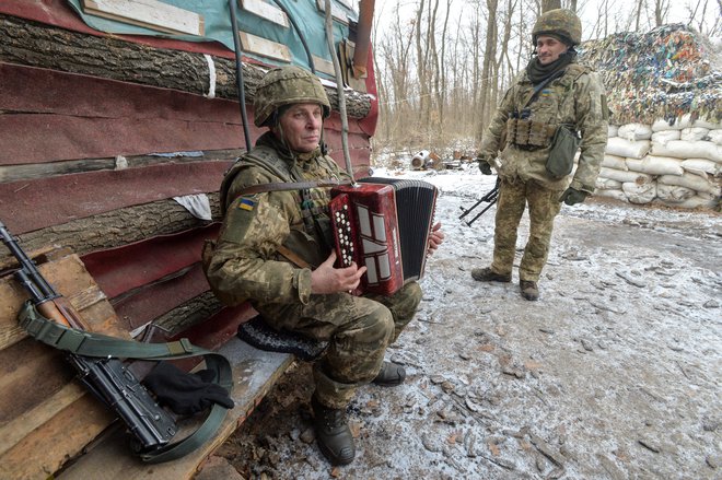 Ukrajinski vojak igra harmoniko na bojnih položajih v bližini mesta Avdiivka v Donjecku, kjer potekajo boji z rusko podprtimi separatističnimi uporniki. FOTO: Oleksandr Klymenko/Reuters