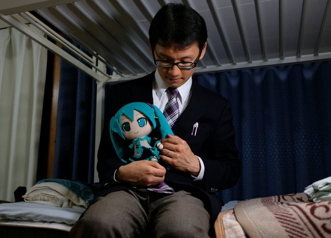 Akihiko Kondo, 35, poses for a photograph with a doll modelled after virtual reality singer Hatsune Miku, wearing their wedding rings, at his apartment after marrying her in Tokyo, Japan November 9, 2018. Picture taken November 9, 2018.  REUTERS/Kwiyeon Ha - RC198773CE30