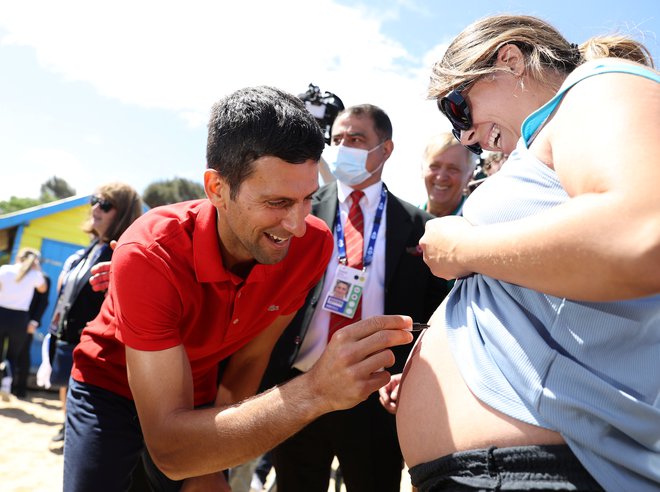 Novak Đoković se je takole včeraj podpisal na trebuh ene od svojih nosečih oboževalk. FOTO: Loren Elliott/Reuters