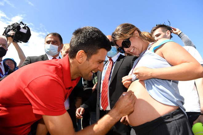 Po finalni zmagi je moral Novak Đoković podeliti številne avtograme navijačem: enega tudi skorajšnji mamici na nenavadno mesto. FOTO: William West/AFP