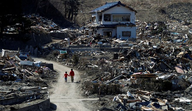 Ljudje hodijo po območju, ki je bilo uničeno zaradi potresa in cunamija 11. marca v Mijaku v prefekturi Ivate. FOTO: Toru Hanai/Reuters