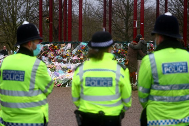 Policisti varujejo osredni del parka Clapham Common, kamor ljudje že več dni prinašajo cvetje v spomin na Sarah Everard. Foto: Hannah Mckay/Reuters