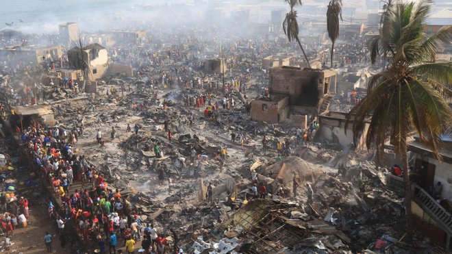 Ljudje si ogledujejo posledice velikega požara, ki je izbruhnil v nelegalnem naselju v Freetownu. Ogenj je požgal na stotine na črno zgrajenih preprostih zgradb in prizadel tisoče ljudi v glavnem mestu afriške države Sierra Leone. FOTO: Saidu Bah/Afp